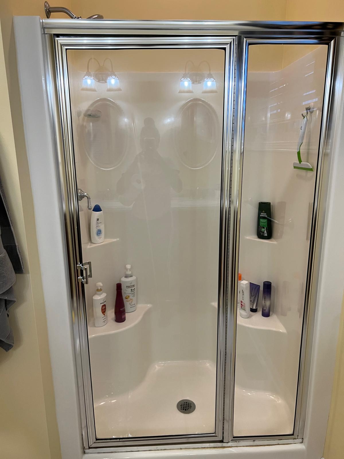 Spotless shower stall with polished glass door after a deep bathroom cleaning